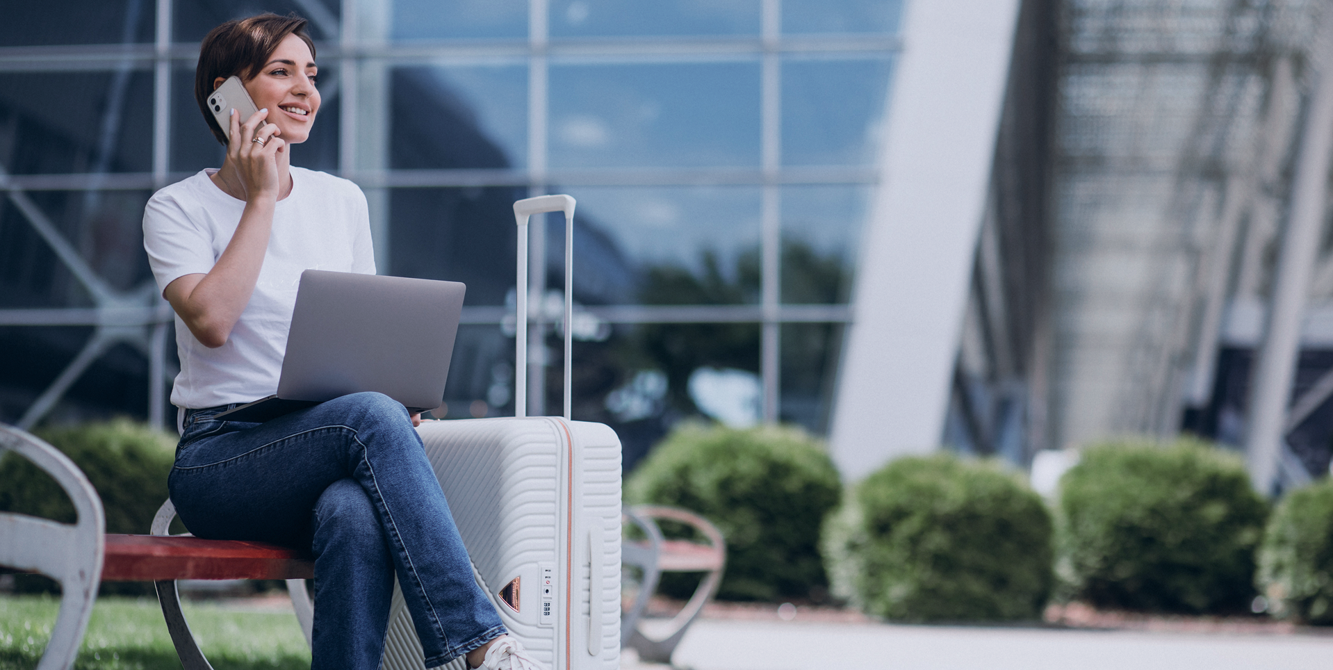 Business traveler on phone with suitcase and laptop