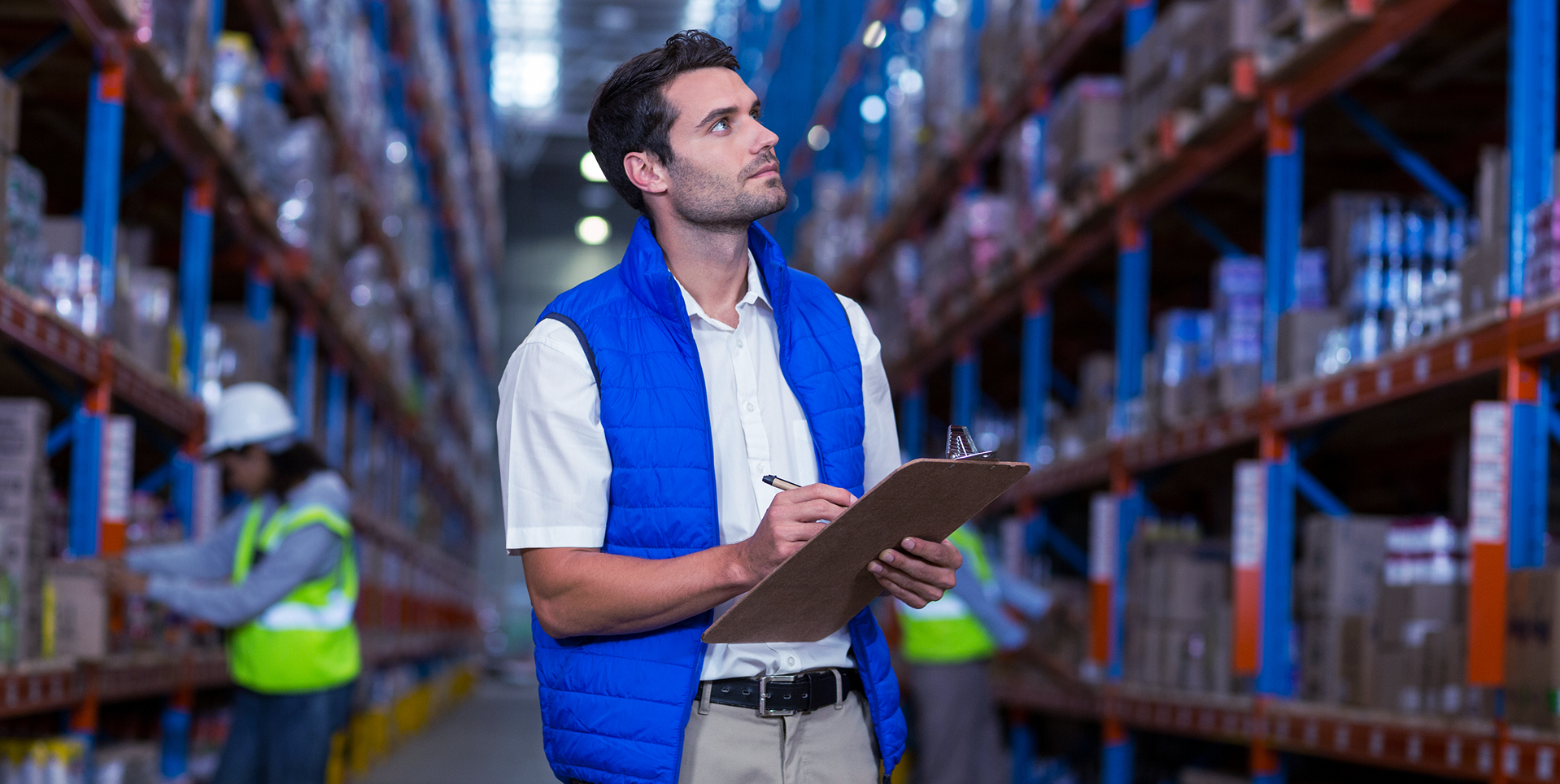 Warehouse worker using tablet among shelves